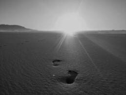Zwei Fußabdrücke im Sand bei Sonnenaufgang